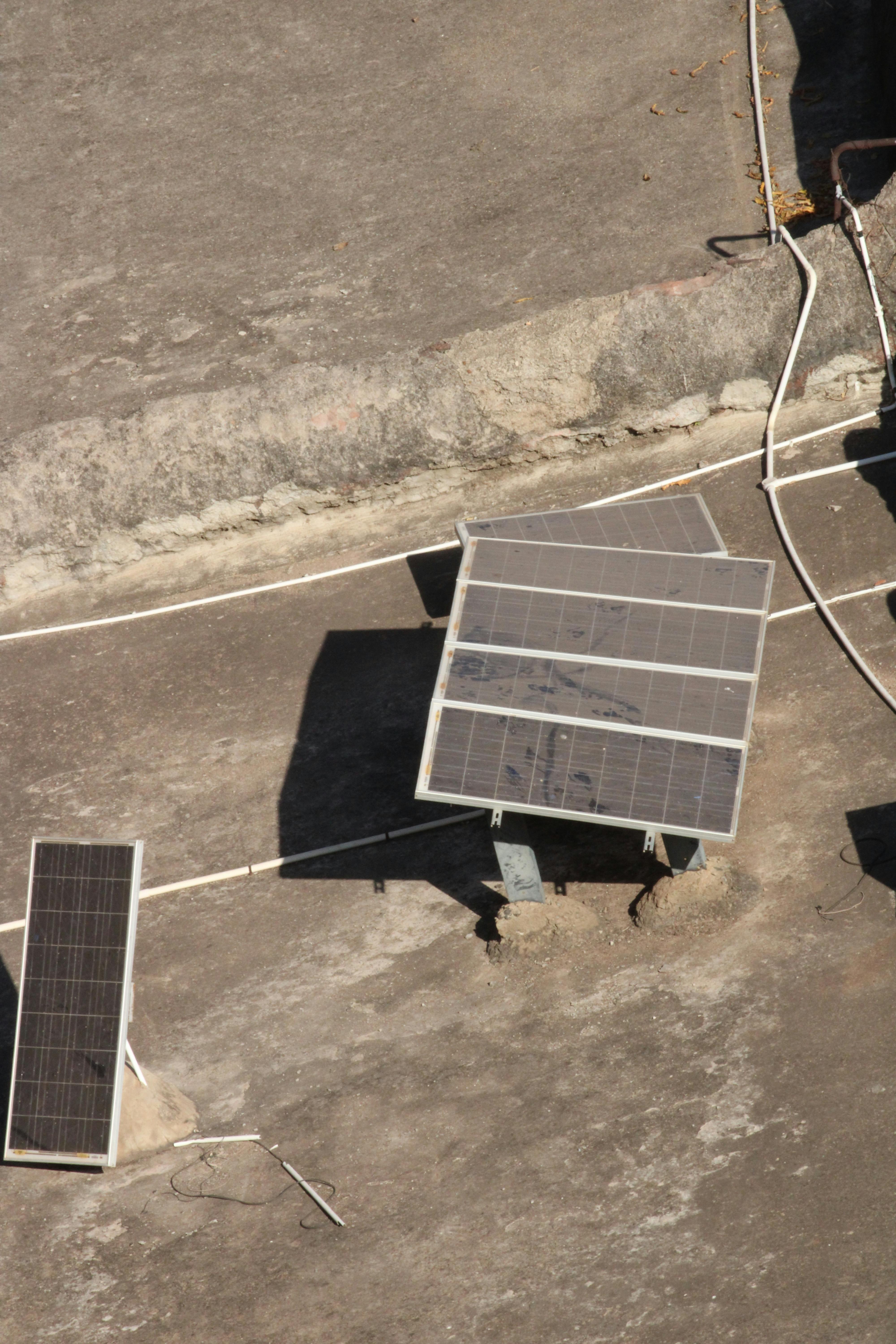 Aerial shot of solar panels on a rooftop in Badami, India under bright sunlight.