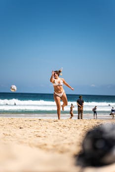 Woman playing volleyball at Sydney beach under clear skies, a perfect summer activity.