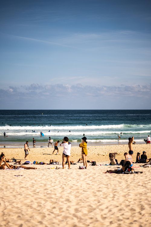 Free People enjoying a sunny day at Bondi Beach, Sydney with waves and clear skies. Stock Photo