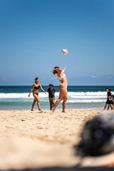 Women playing volleyball on a sunny beach in Sydney, perfect summer fun.