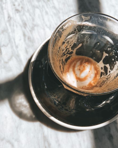 Free Empty coffee glass with latte art remnants in sunlight on a marble table. Perfect for beverage concepts. Stock Photo