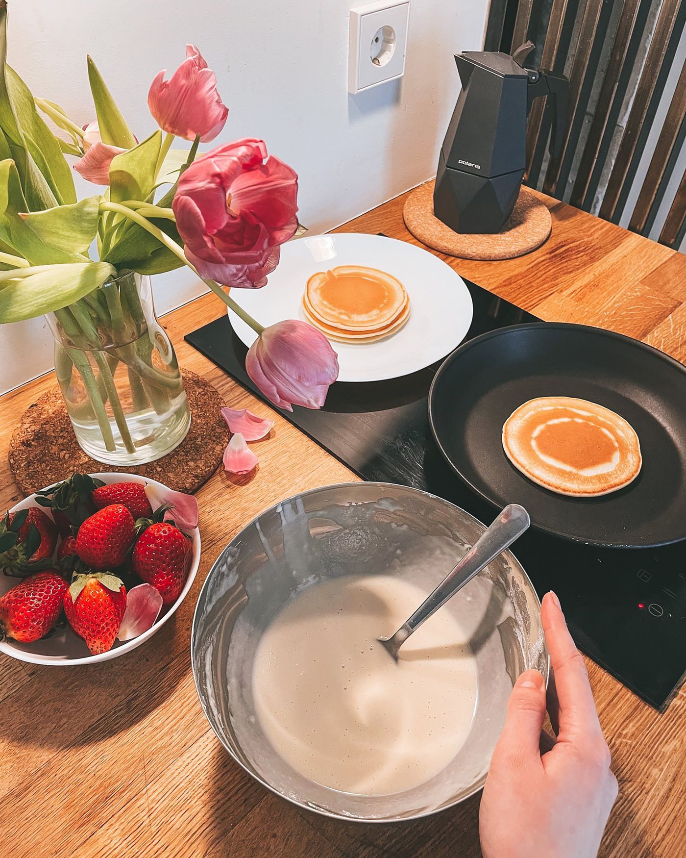 Homemade pancakes served on a plate beside a pan in a home kitchen
