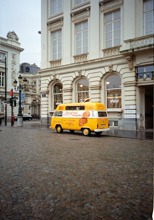 A yellow van parked on a cobblestone street