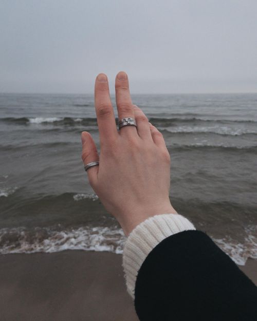Free Close-up of a hand with silver rings against the Gdańsk seashore's cold backdrop. Stock Photo