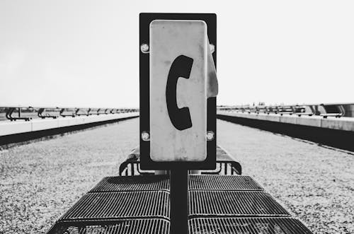 A black and white photo of a phone on a train platform