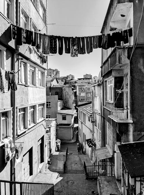 A black and white photo of a street with clothes hanging on the line