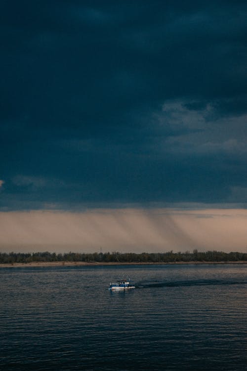 A boat is floating on the water under a dark sky
