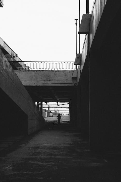 A black and white photo of a man walking down a walkway