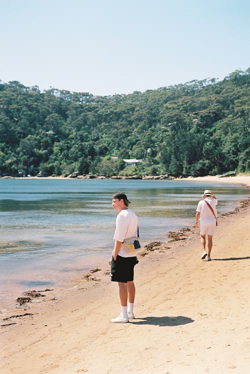 A man and woman walking on a beach near water