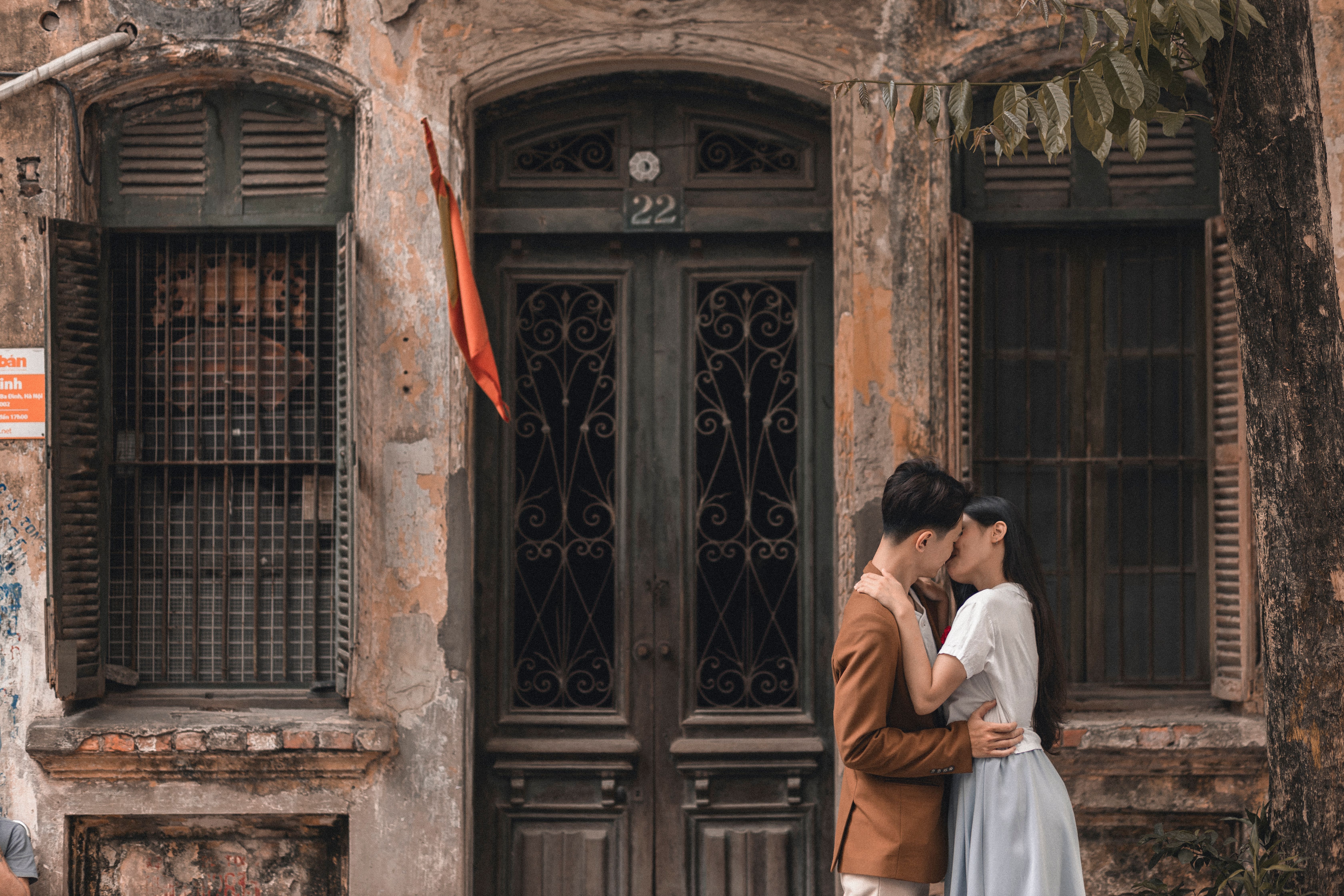 Young couple embracing in front of an old rustic building, conveying romance and intimacy.