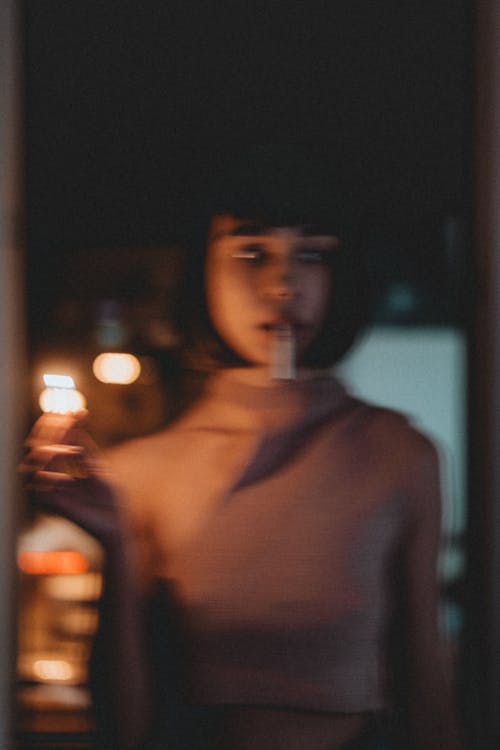A woman holding a lit candle in front of her face