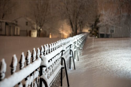 A fence is covered in snow at night