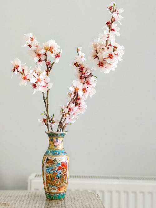 A vase with pink flowers on it sitting on a table