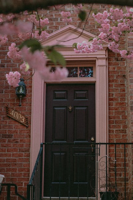 A beautiful brick house entrance framed by pink blossoms, creating a vibrant and inviting facade.