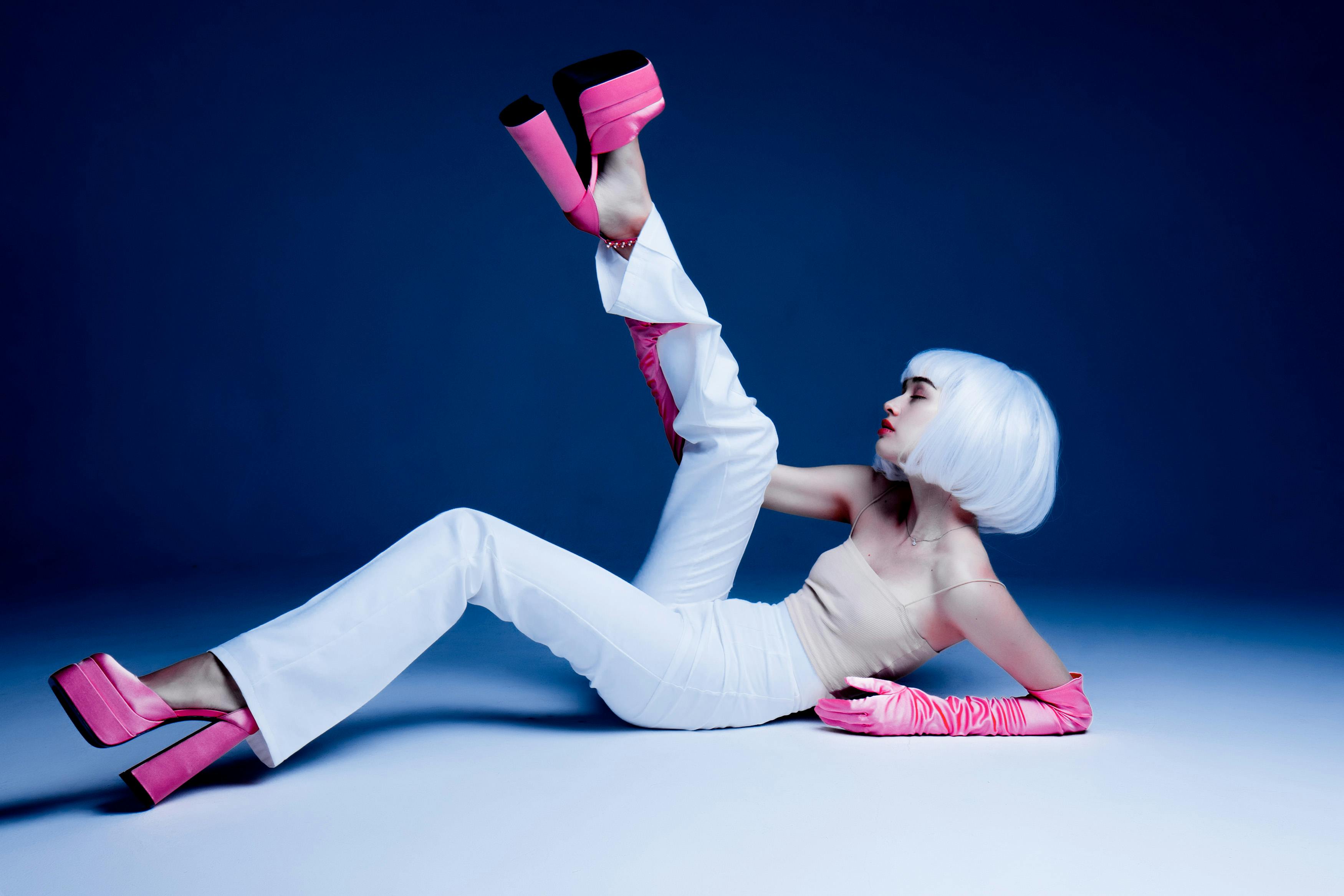 Artistic portrait of a woman in pink heels and gloves striking a dynamic pose.