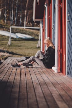 一名金发女子随意地坐在外面的木甲板上，享受着阳光