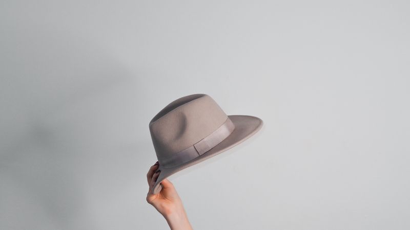 A beige felt hat held against a plain white ground &mdash; photo by Laura Chouette on Pexels