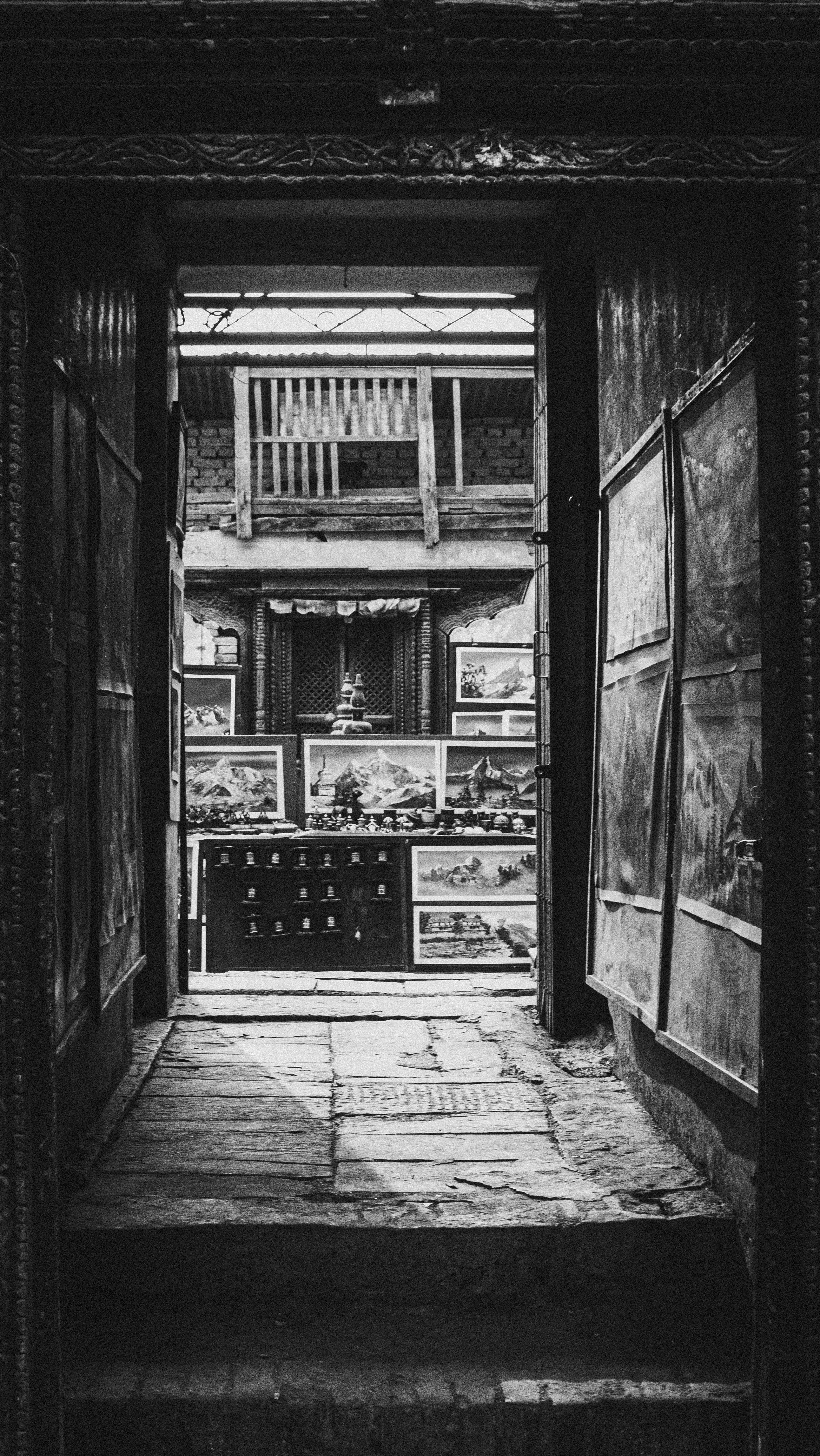 Black and white photo of a narrow urban corridor featuring traditional artwork.