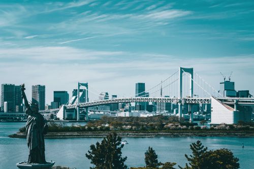 Free A scenic view of Tokyo's Rainbow Bridge and skyline with the Statue of Liberty replica. Stock Photo