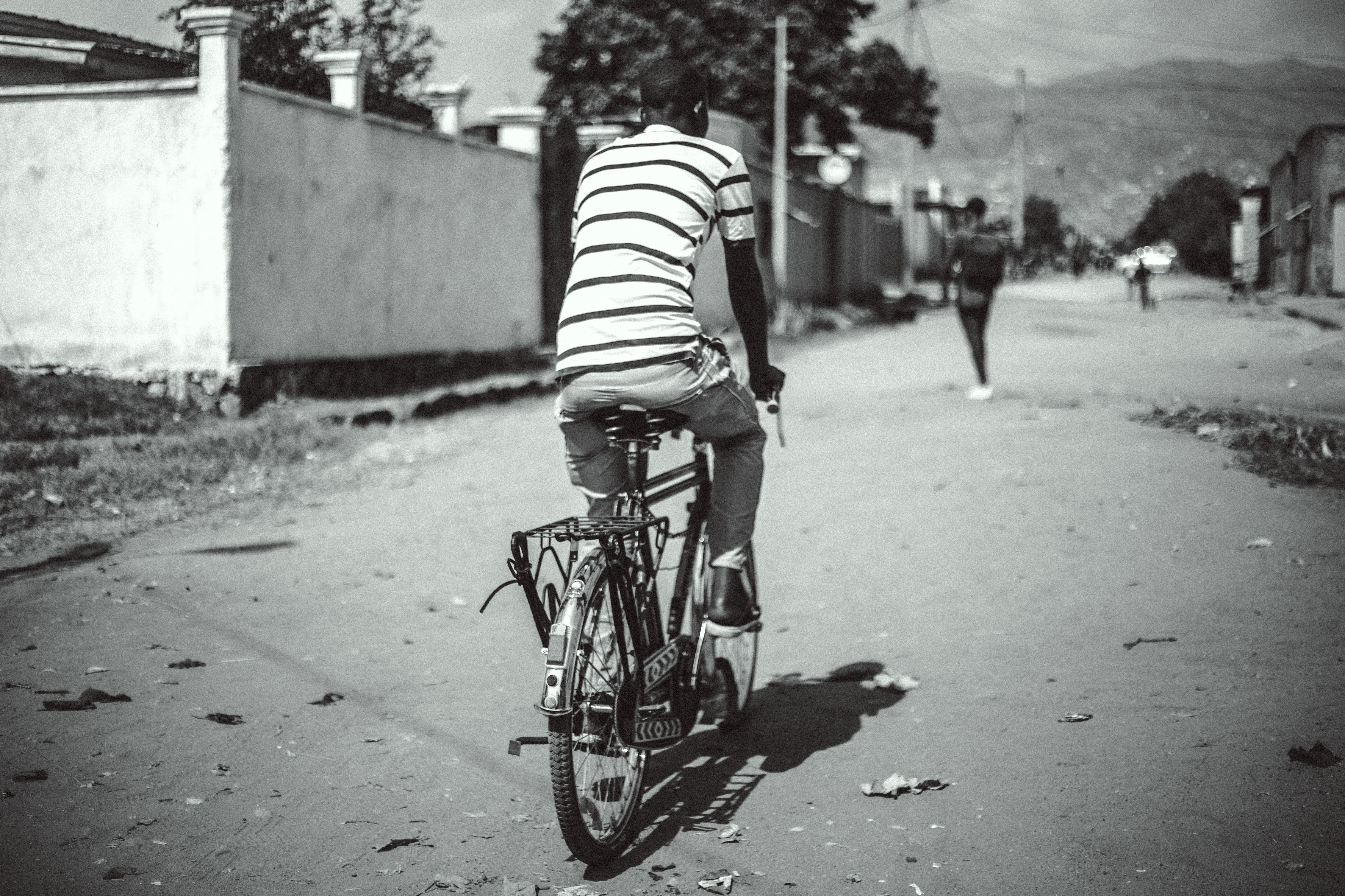Back view of man riding bike in village, Burundi