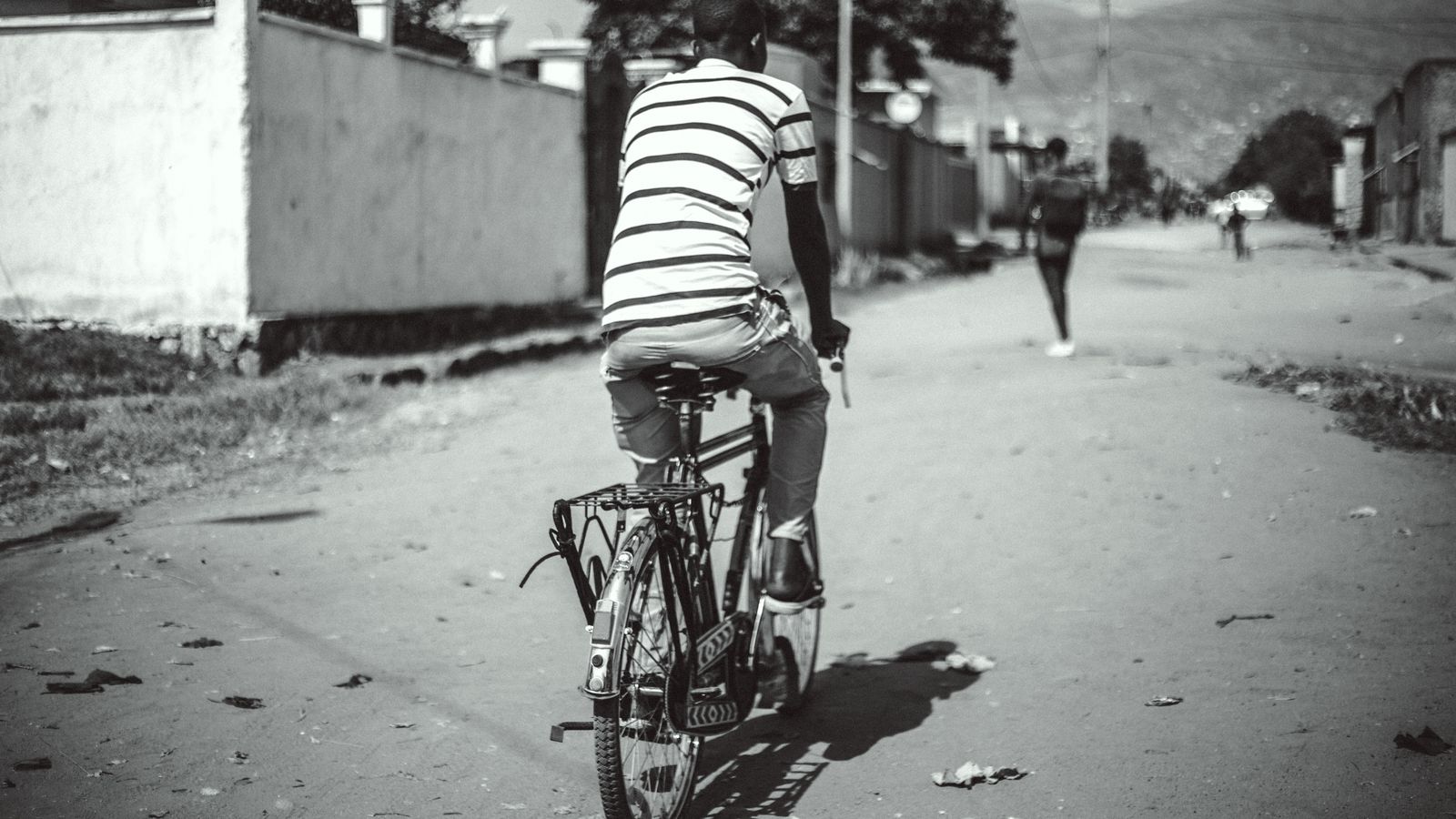 Back view of man riding bike in village, Burundi
