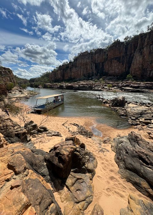 Free A tranquil river gorge scene with rocky cliffs, flowing water, and a boat under dramatic clouds. Stock Photo