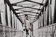 一位年轻的时尚摄影师手拿相机走在金属桥上