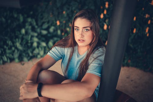Free Woman Sitting And Leaning On Black Post Stock Photo