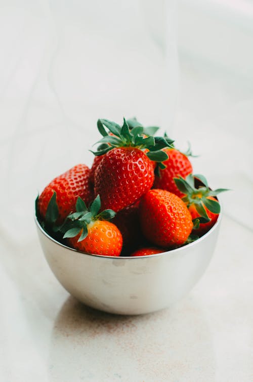 A silver bowl filled with strawberries on a table