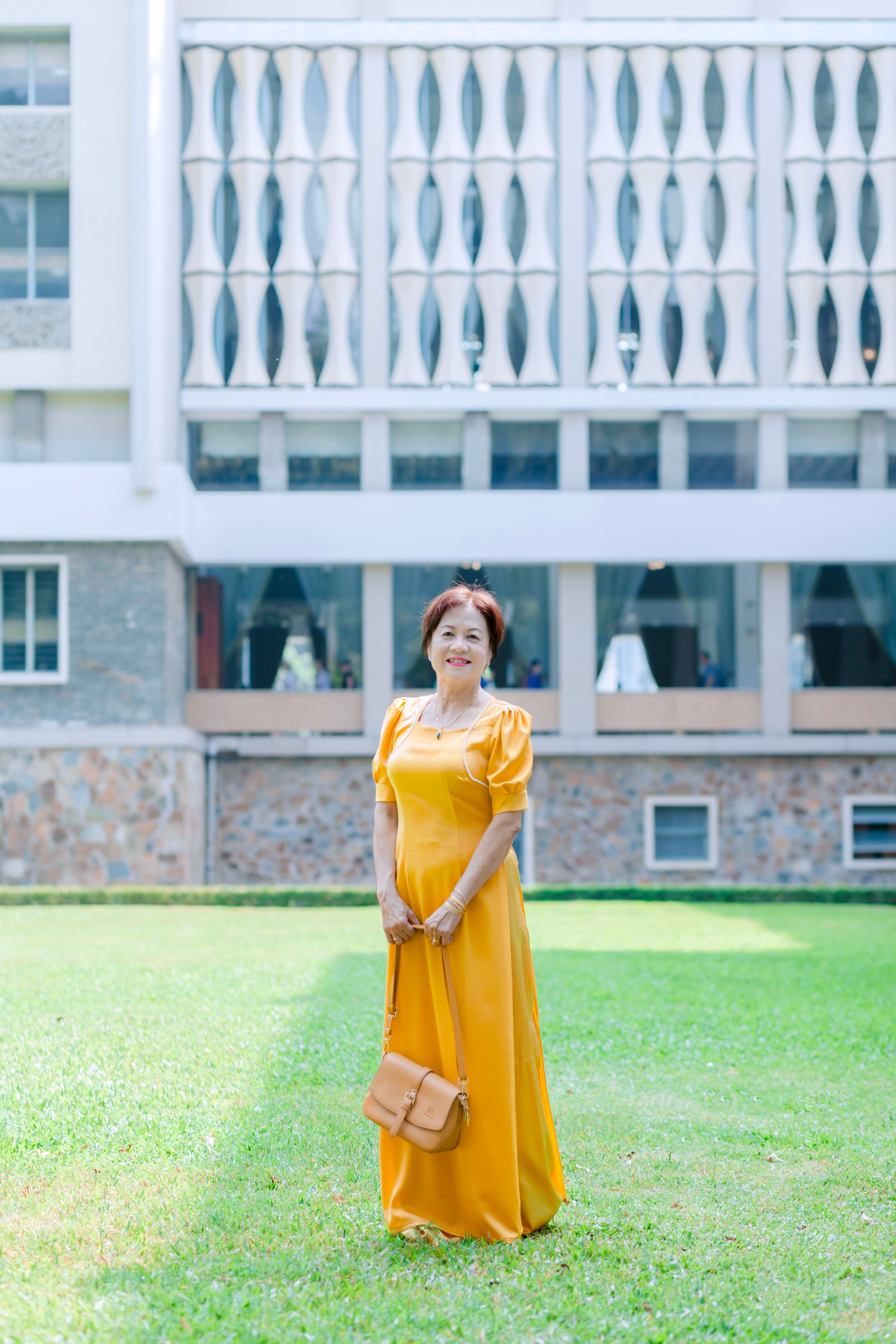 A woman in a yellow dress standing in front of a building · Free Stock ...