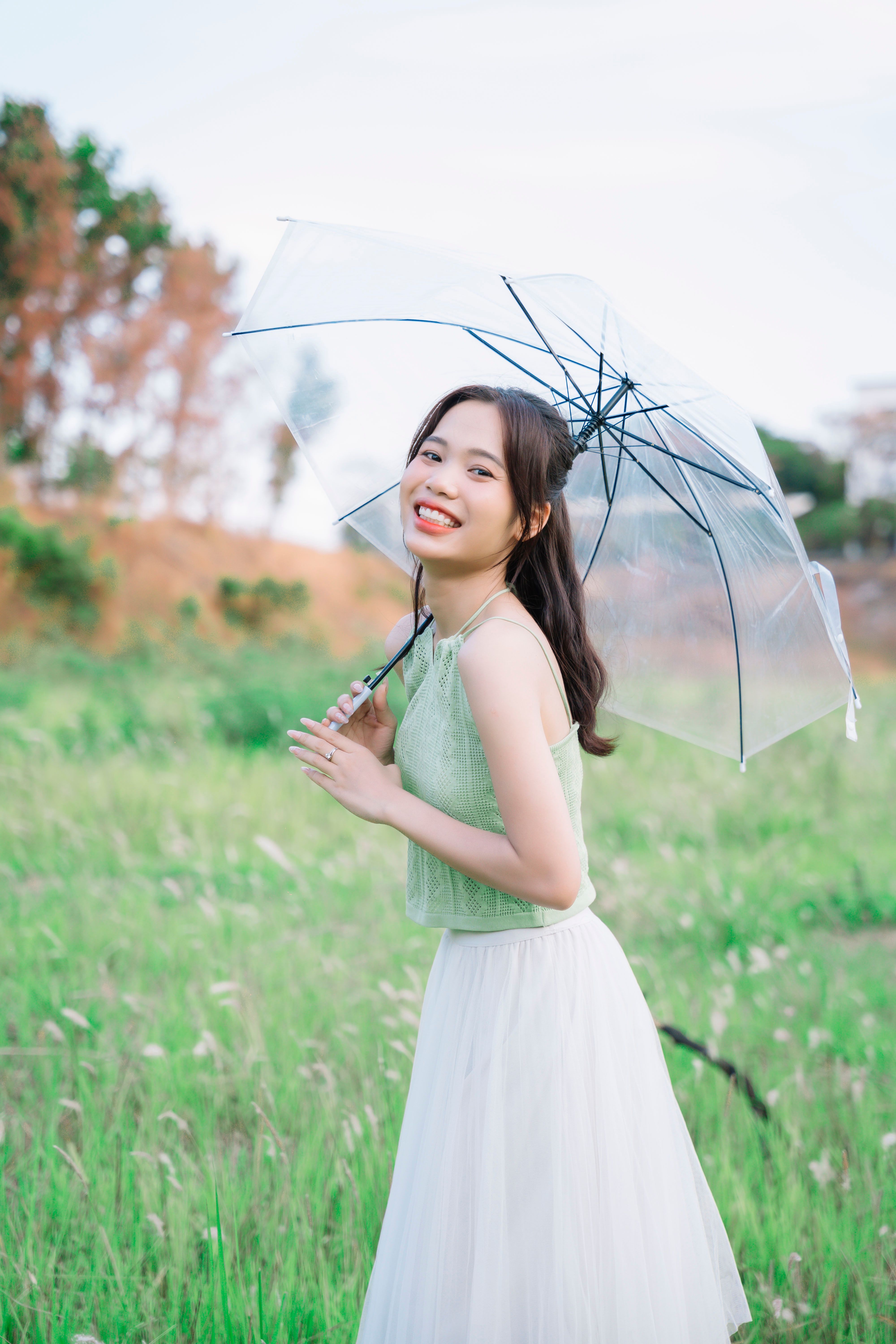 Woman Standing on a Meadow and Holding an Umbrella · Free Stock Photo