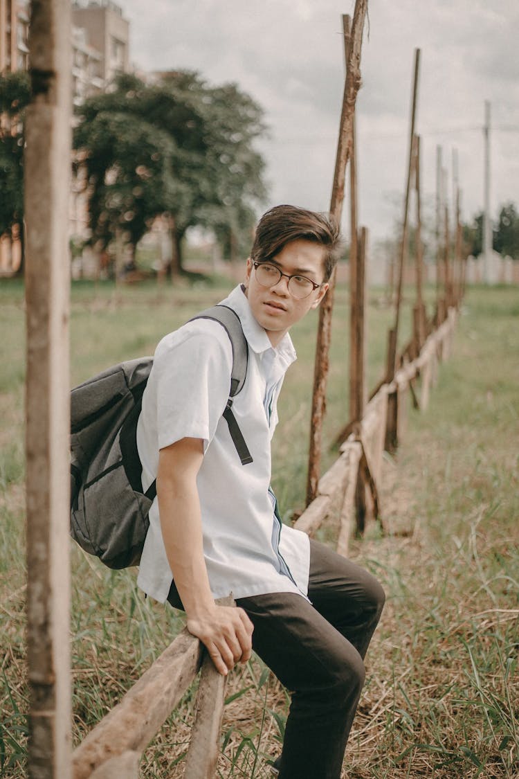 Student Sitting On A Wooden Fence