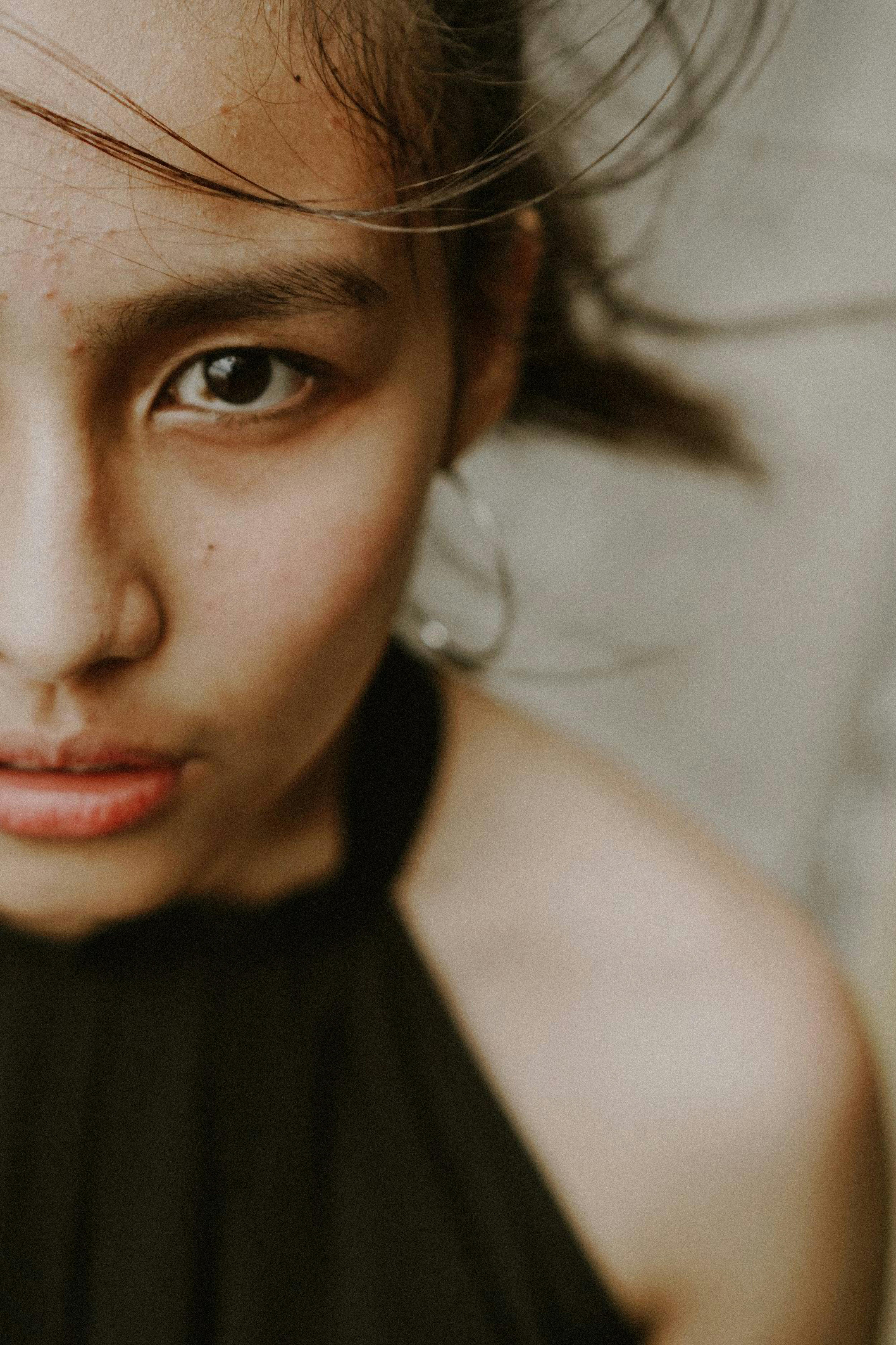 Artistic close-up portrait capturing the intense gaze of a young Asian woman with wind-swept hair.