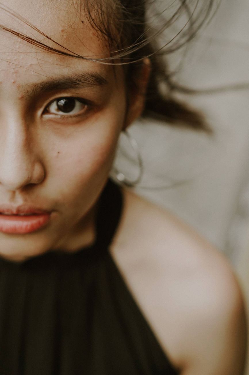 Artistic close-up portrait capturing the intense gaze of a young Asian woman with wind-swept hair.