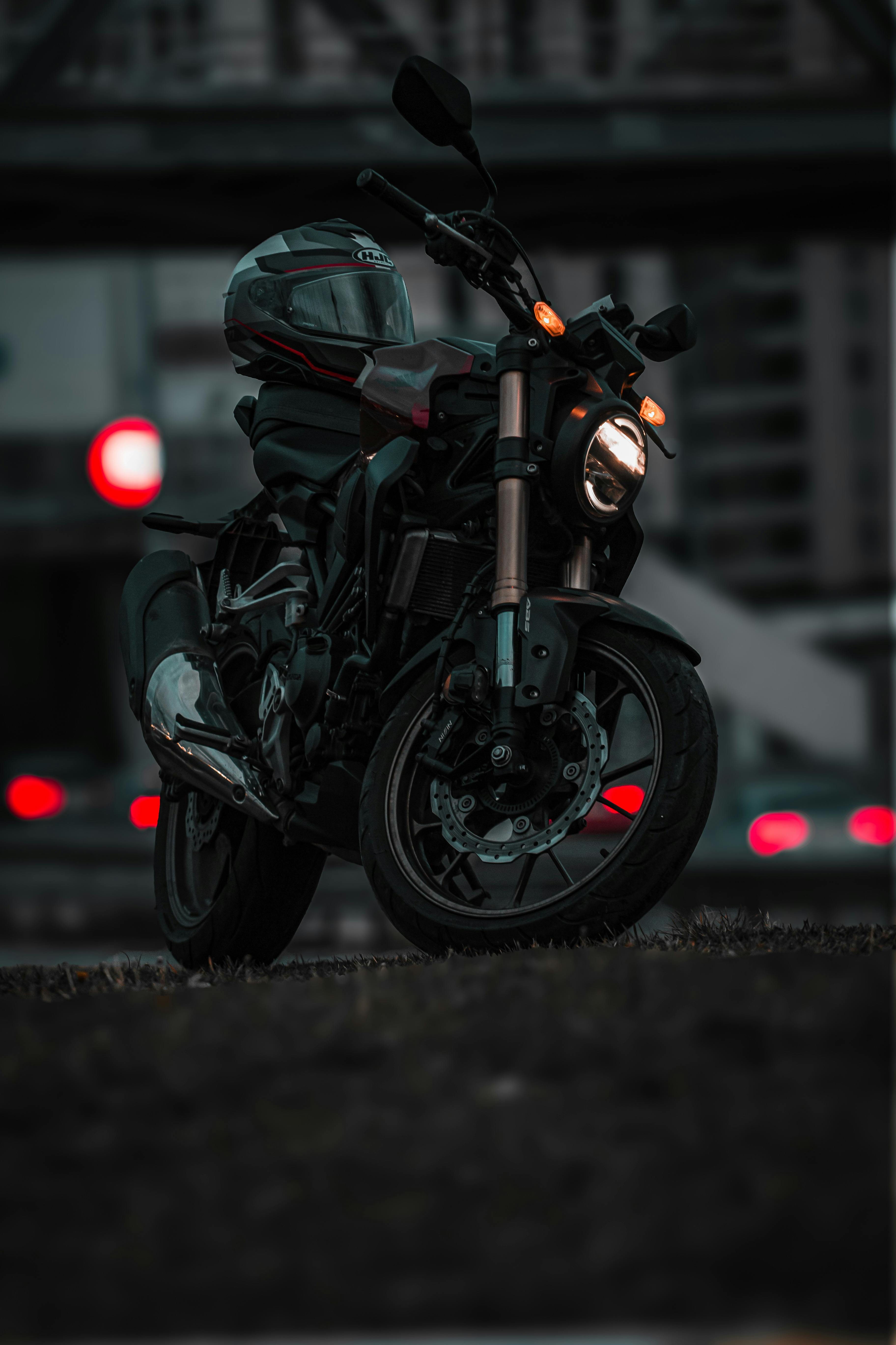 Free A dramatic shot of a motorcycle parked at dusk with the helmet on the seat highlighting urban transportation. Stock Photo
