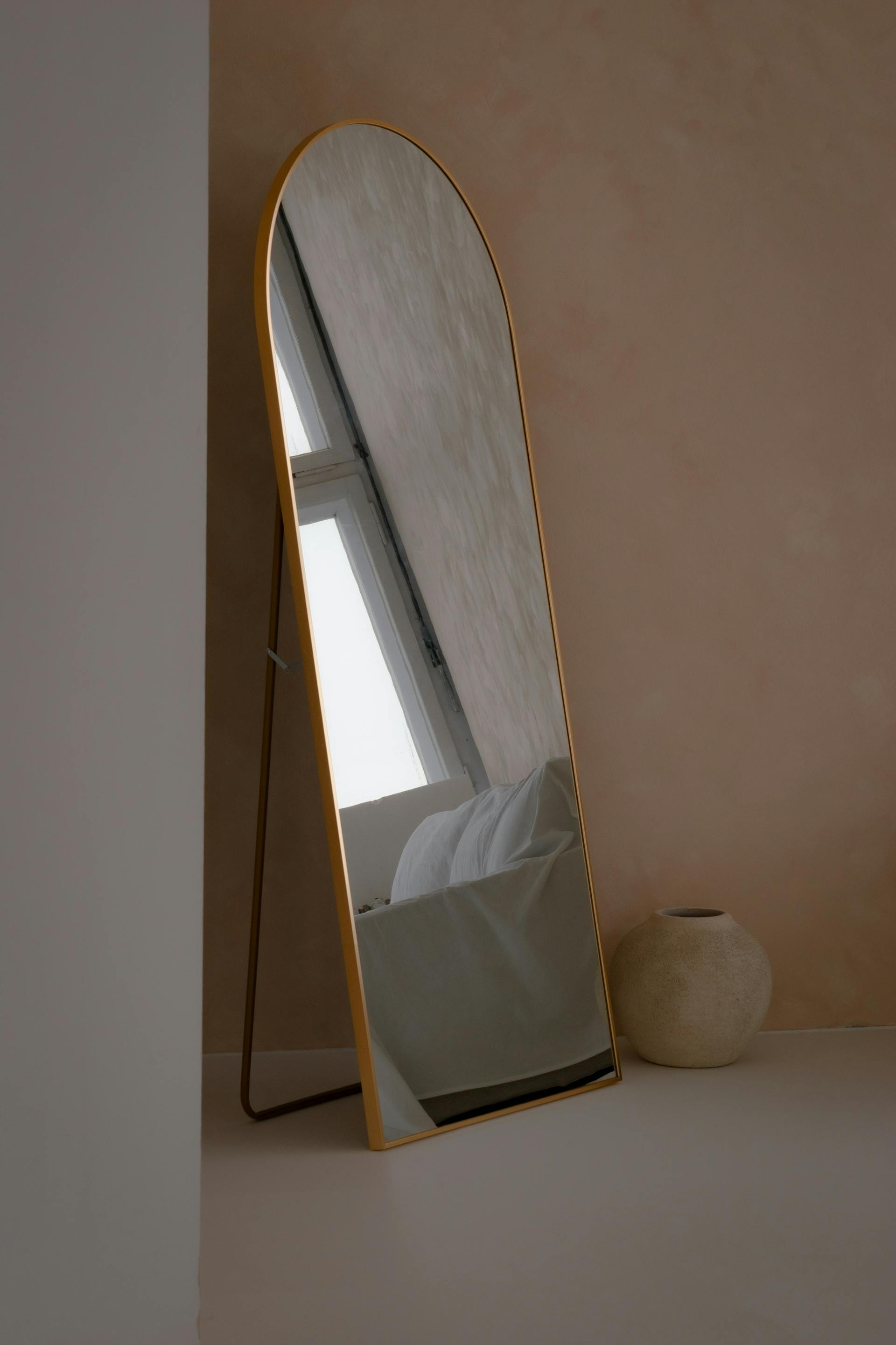 Aesthetic minimalist interior with a standing mirror reflecting a window light.