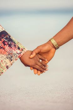 Close-up of a couple holding hands on a sunny day, emphasizing love and connection.