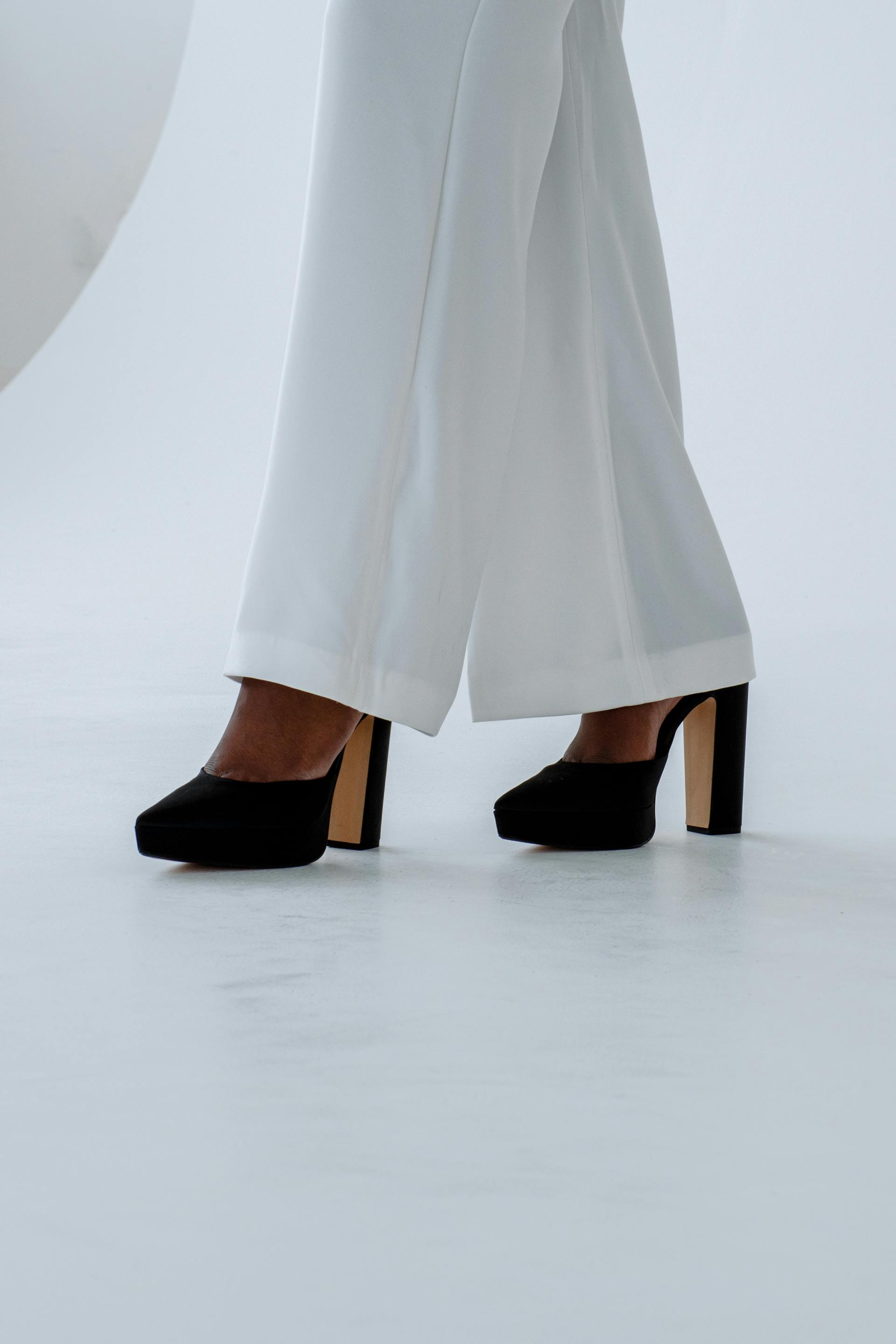 A stylish depiction of elegance with black high heels and flowing white pants, perfect for fashion enthusiasts.