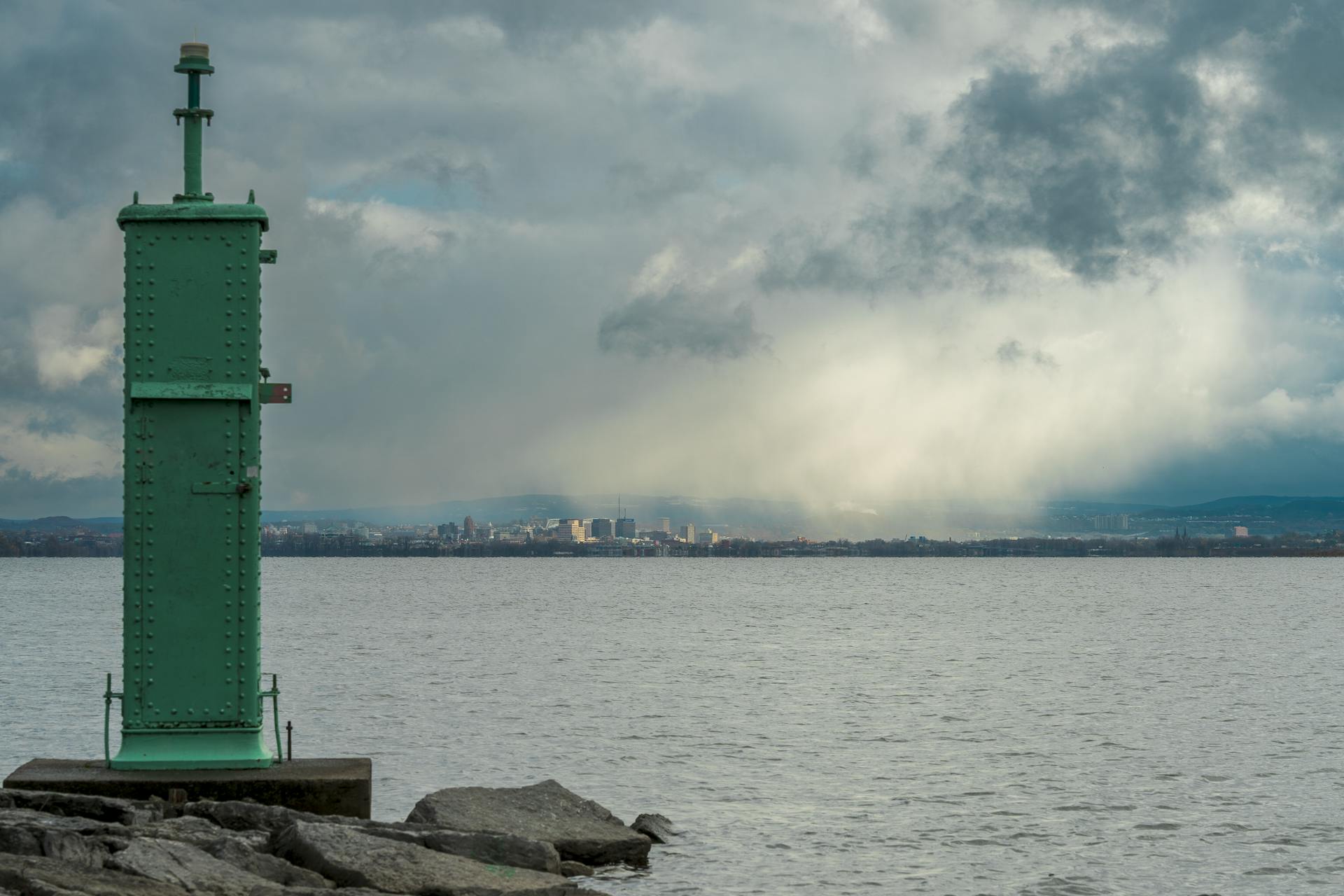 View of Syracuse skyline across Onondaga Lake under stormy clouds.