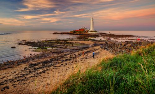 Free A picturesque lighthouse on a coastal landscape during sunset with colorful skies. Stock Photo