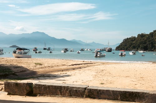 A beach with boats and mountains in the background
