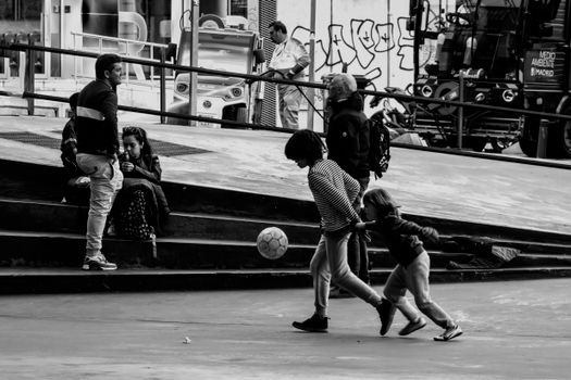 Children playing soccer in a Madrid skate park, capturing urban leisure and community spirit.