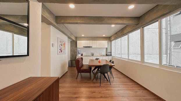 A sleek modern kitchen dining area with wooden floors and bright lighting in Mexico City.