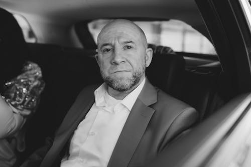 A man in a suit sitting in the back of a car