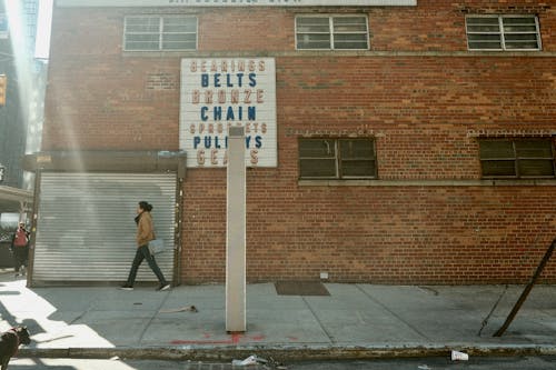 A man walking down the street in front of a brick building