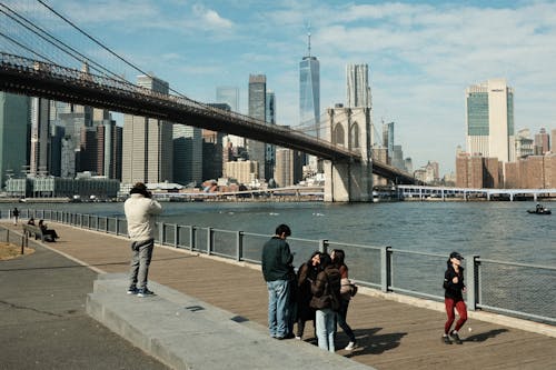 People are walking on the boardwalk near the brooklyn bridge