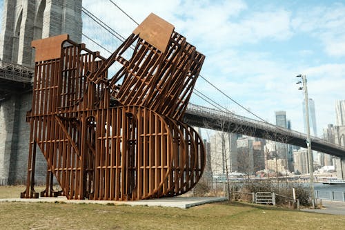 A large metal sculpture in front of the brooklyn bridge