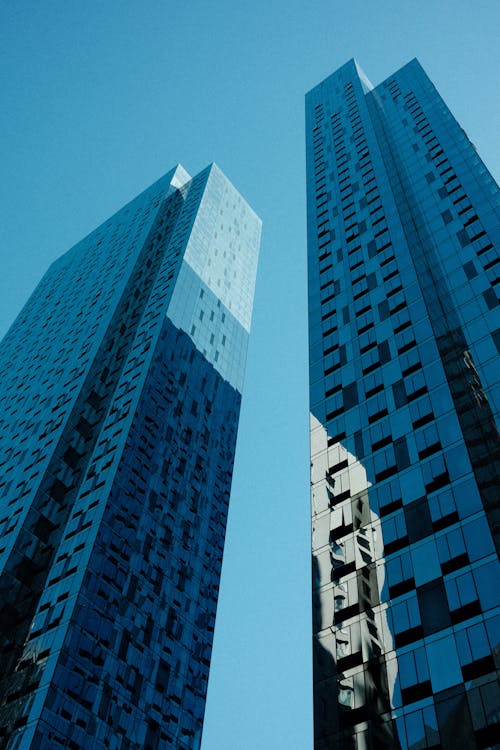 Two tall buildings with windows and a blue sky