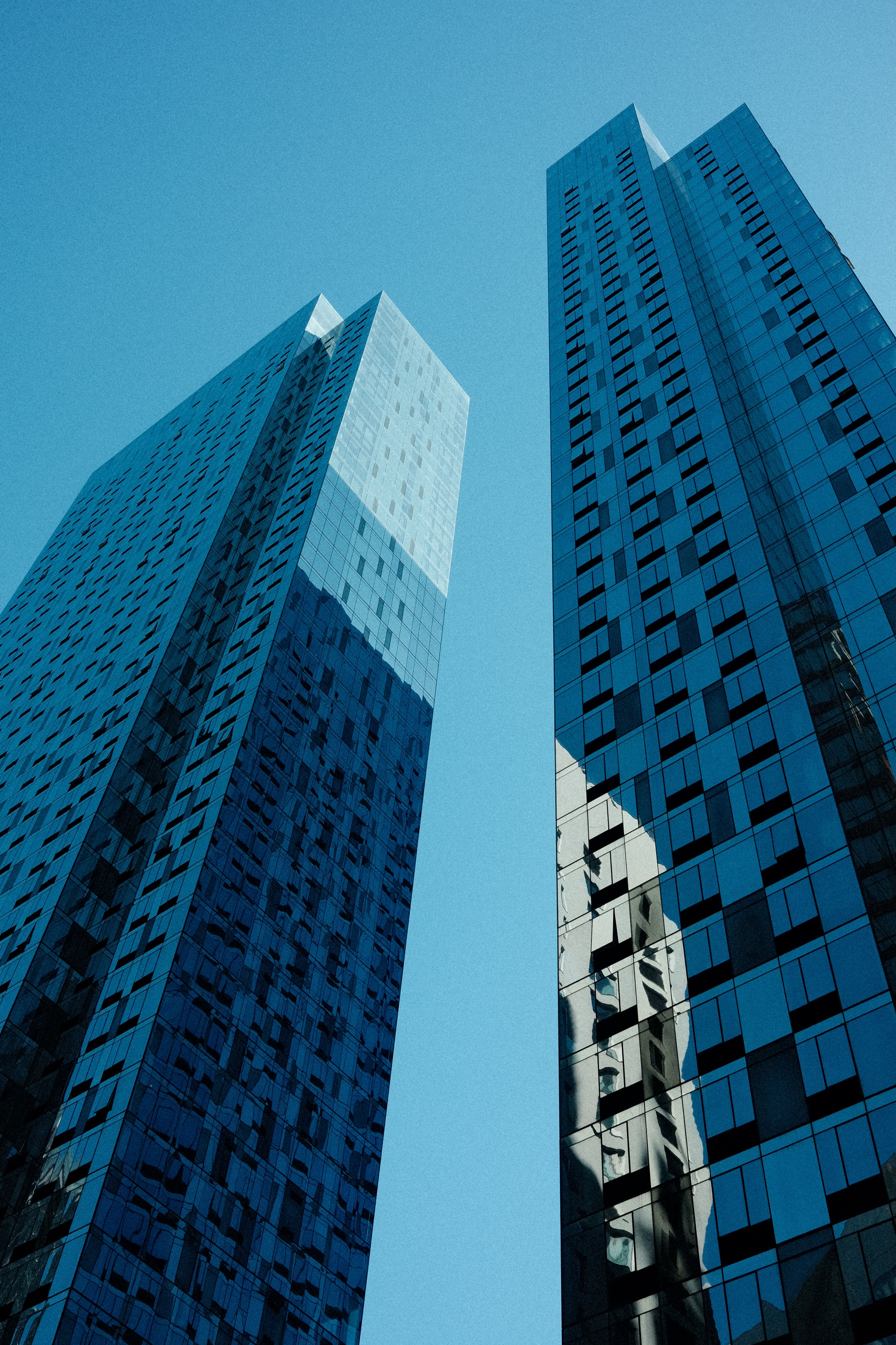 Two tall buildings with windows and a blue sky · Free Stock Photo