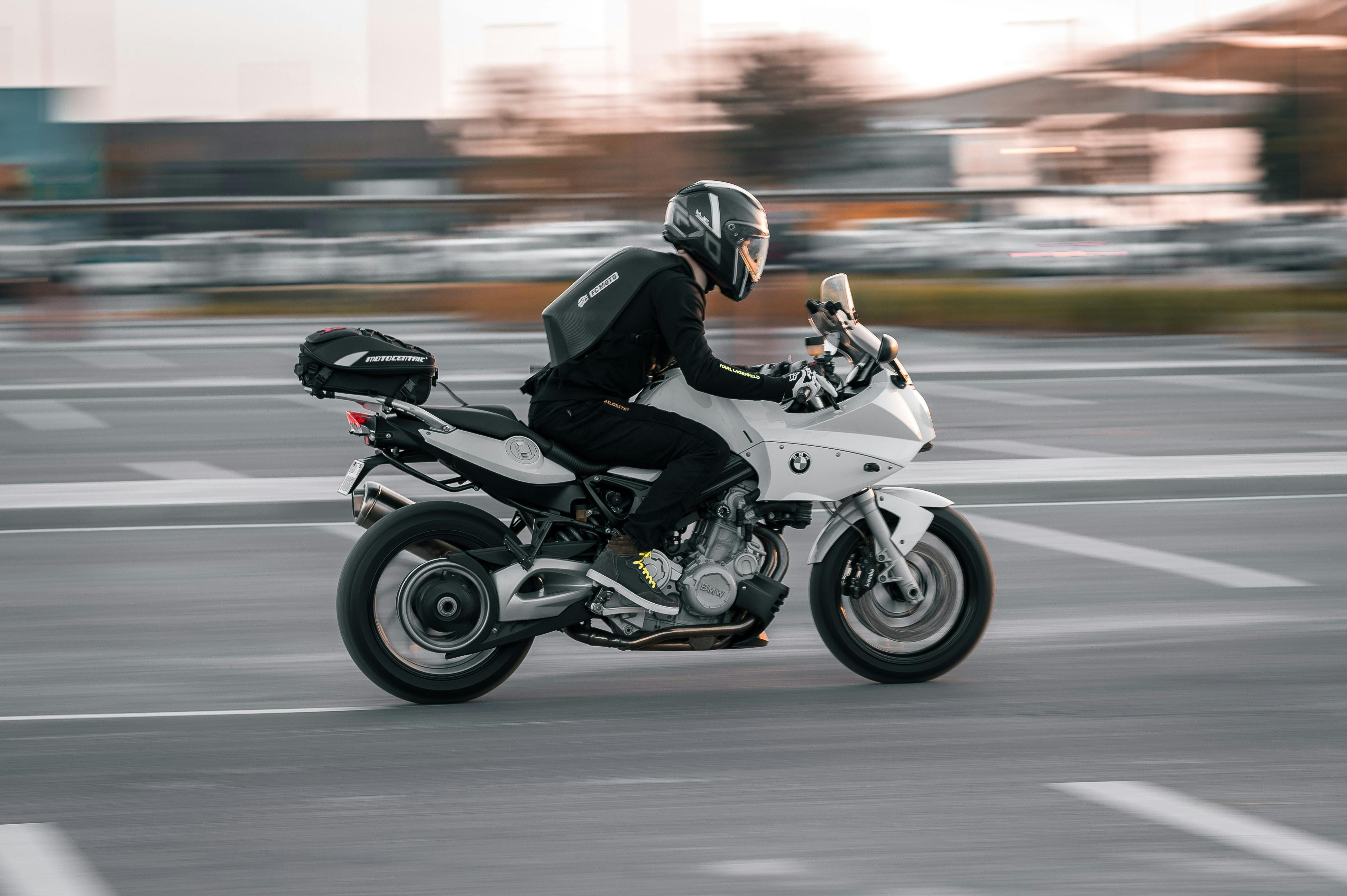 A motorcyclist wearing a helmet rides through the city streets of Abu Dhabi